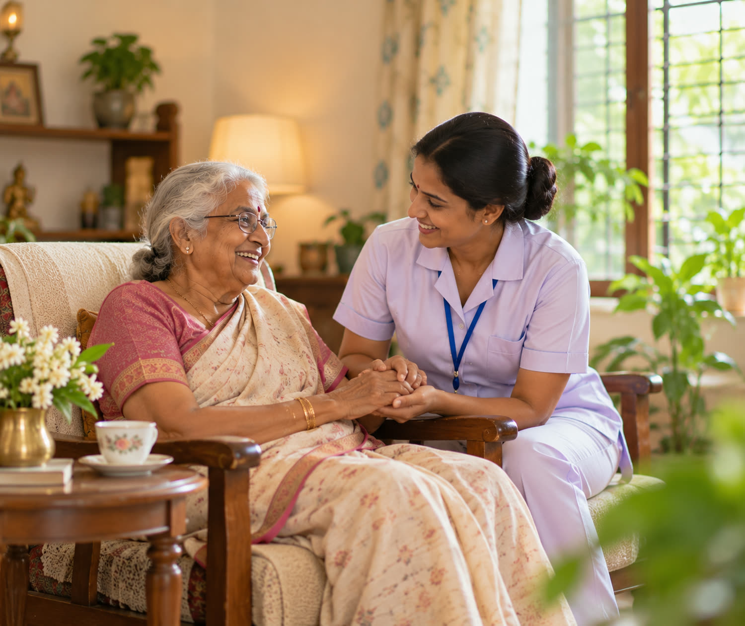 A caregiver holding the hand of a smiling elderly woman in a cosy living room